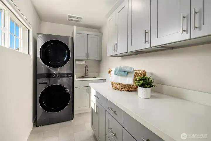 The laundry room features lots of storage cabinets and a quartz countertop for folding. These were additional upgrades installed by the owner.