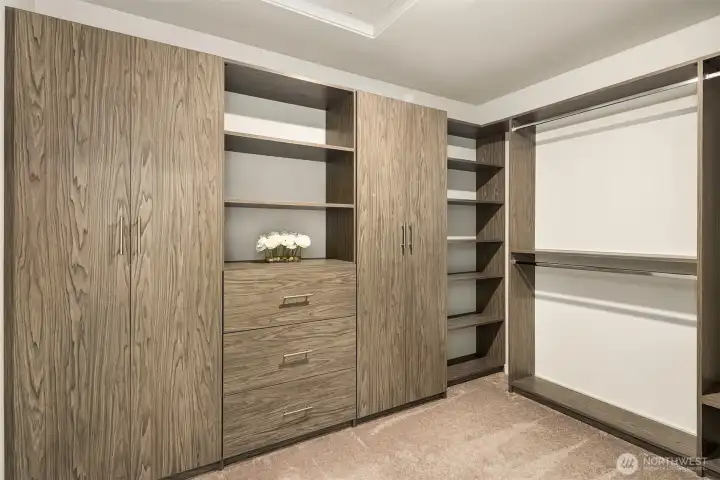 Primary suite walk-in-closet has built-in organizers, shelves, hanging space, and drawers.