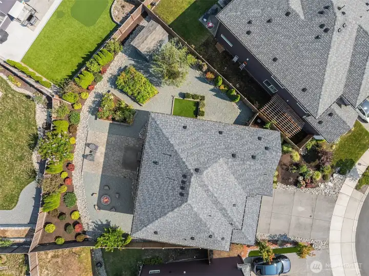 Aerial view directly overhead of property. From here you can see the fire pit area, the large patio, the flower and raspberry beds, the garden shed (in the top fenced in corner), the pet care area, and the different landscaping with low maintenance plants.