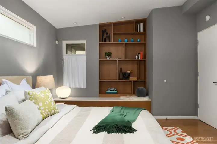 Custom walnut shelving with 3 large drawers underneath the window seat offers functional beauty in the primary bedroom.