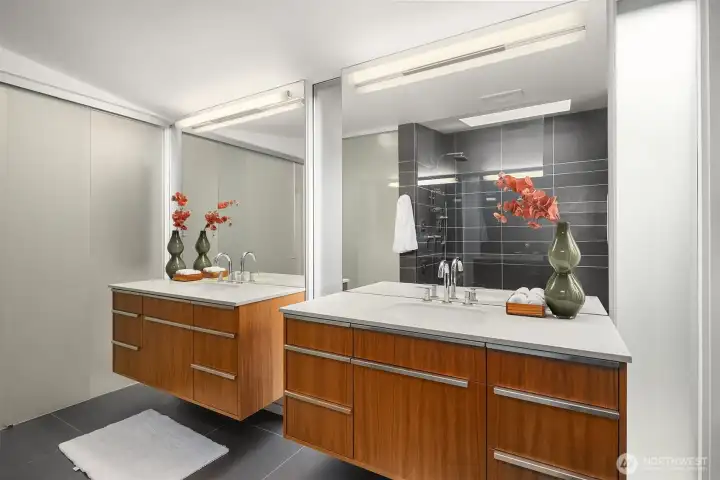 A frosted wall and sliding door separates the primary bath from walk-in closet and adjacent bedroom while still allowing light to flow.