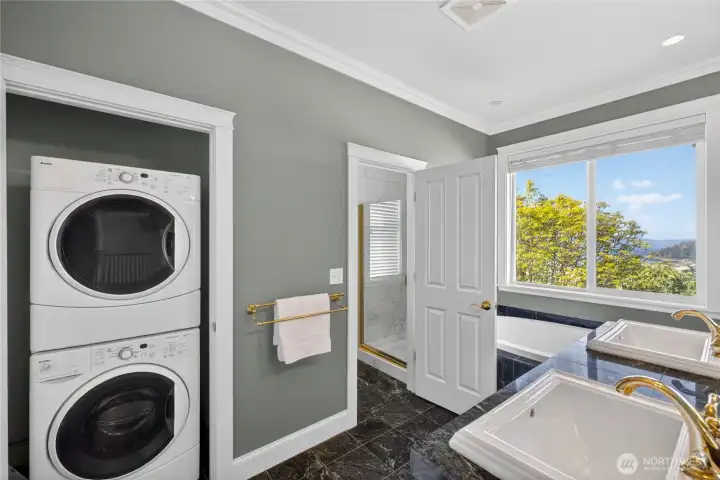 And in the primary bathroom, a full stacked washer and dryer. The shower is built of white marble tile.