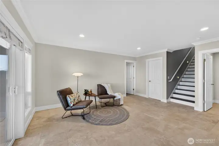 The stairwell in the entry leads to this spacious downstairs living area. Those are real Travertine floors! The door to the right is a second laundry room for downstairs.