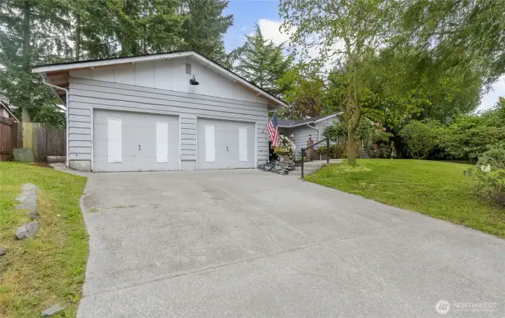 Spacious two-car garage with barn-style lighting and an oversized concrete driveway offering ample parking and easy access.