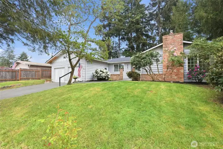 A second angle showcasing the home's clean roofline, attached garage, and manicured grounds with colorful seasonal blooms.