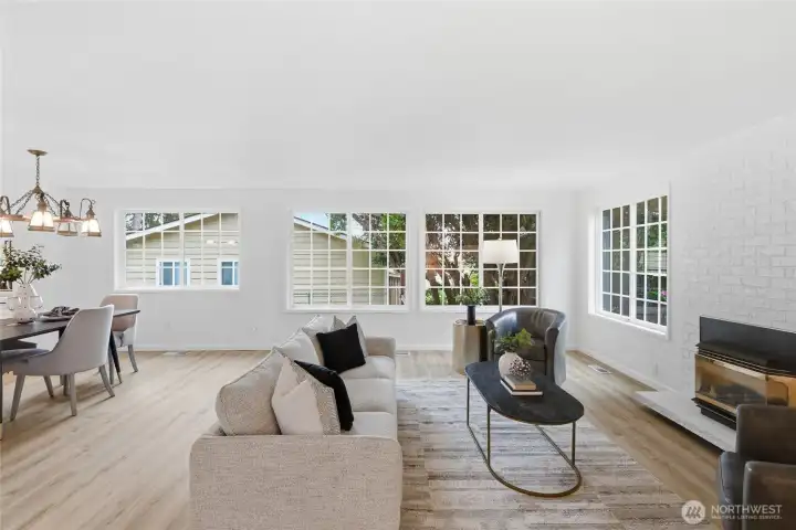 Wide-angle view captures the seamless connection between the living and dining areas, with a bank of grid windows flooding the space with natural light.