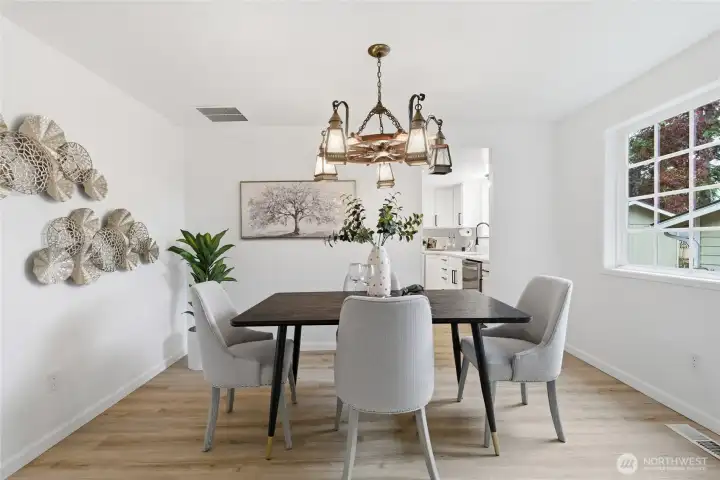 Defined dining space featuring a statement brass lantern chandelier, wood-look floors, and direct sightlines to the updated kitchen.