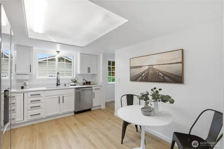 Additional kitchen perspective reveals a sunny eat-in nook with room for a bistro table, complementing the clean white cabinetry and stainless finishes.