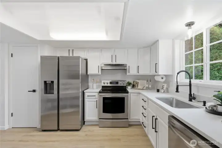 Full kitchen layout featuring a full suite of stainless appliances including a French door refrigerator, electric range, and dishwasher — all set against crisp white cabinetry and quartz surfaces.