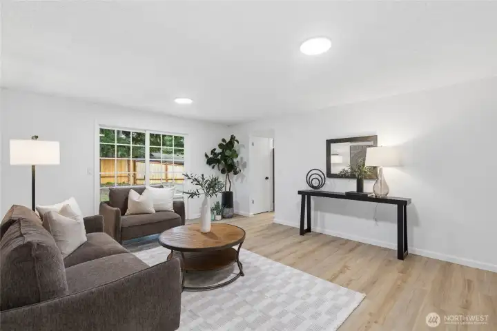 Alternate angle of the family room highlights the open layout, wood-look floors, and easy flow toward the entry and kitchen.