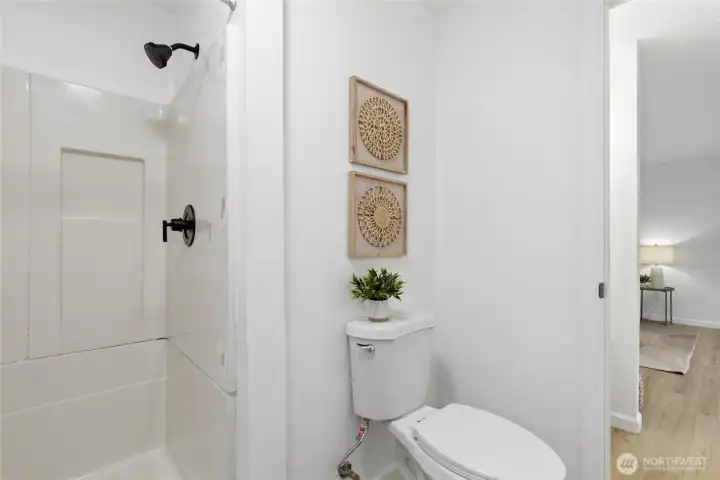 Primary shower withblack fixtures and clean white surround, offering a crisp, updated look.