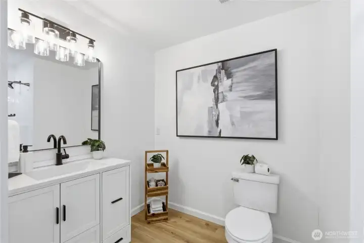 Updated full bath featuring a white shaker vanity, quartz countertop, black hardware, and modern glass globe lighting.