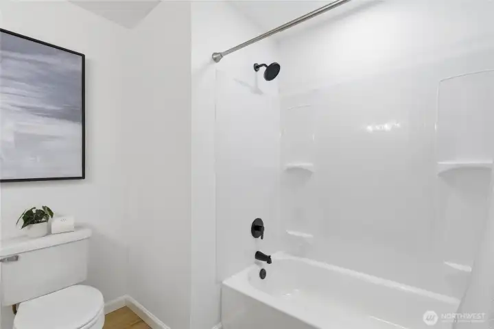 Tub/shower combo with matte black fixtures and a clean white surround — fresh and move-in ready.