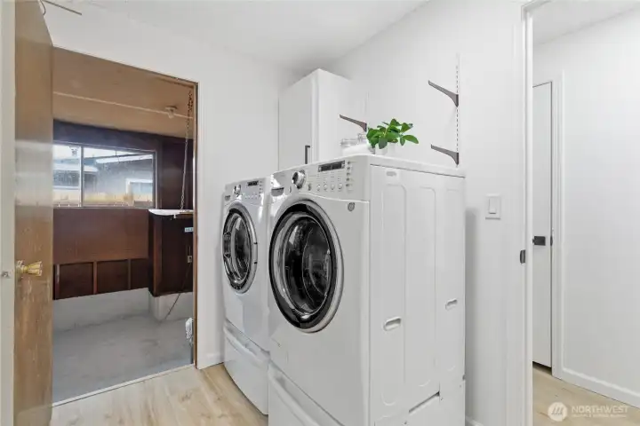 Dedicated laundry space with full-size front-load washer and dryer, upper cabinetry, and direct access to the garage.
