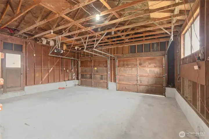Spacious two-car garage with concrete floor, opener, and ample room for vehicles, storage, or a workspace.
