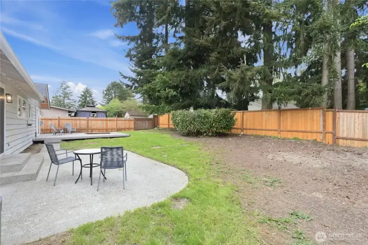 Fully fenced backyard with a concrete patio, lawn area, and a wood deck — a great setup for outdoor entertaining.