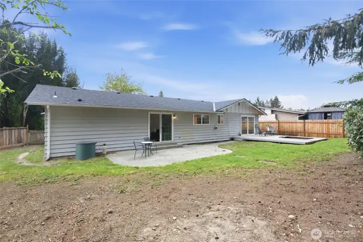 Back of the home showcasing dual sliding glass door access points, a patio, and the wood deck with room to expand the yard.