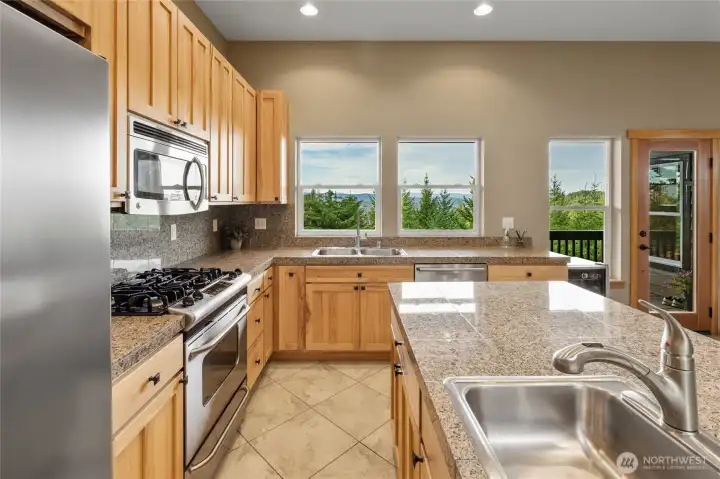 Well-appointed with a stainless steel appliance suite, the kitchen includes a propane range, beverage refrigerator, dishwasher, microwave, refrigerator, and both a main sink and convenient prep sink.