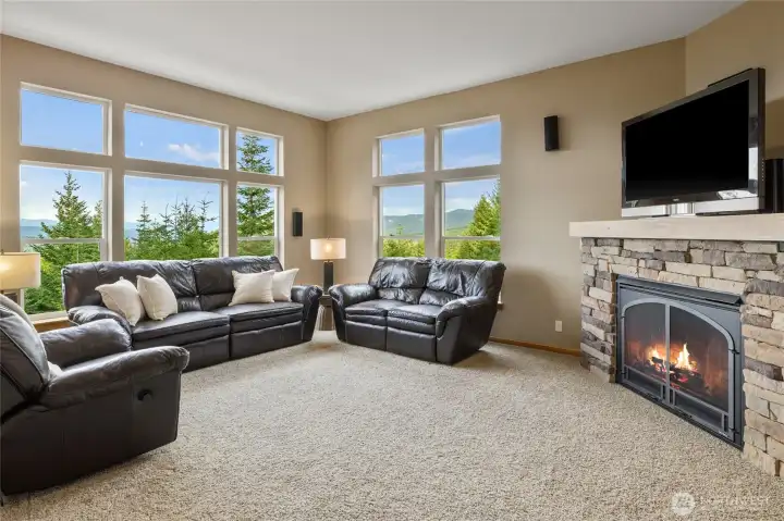 The living room is anchored by a beautiful rock propane fireplace with a wood mantel, while generous windows capture the surrounding mountain scenery.