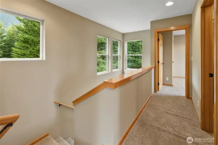A view of the upper-level hallway and stairwell, where abundant natural light highlights the home's quality craftsmanship.