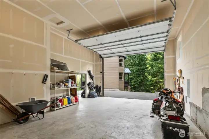 The larger bay comfortably accommodates up to four vehicles and features a heated interior, an RV-height door, electric openers, and welder-ready wiring.