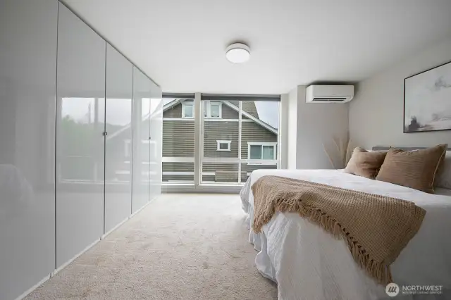 Primary suite with oversized windows and custom wall-to-wall built-in wardrobes.
