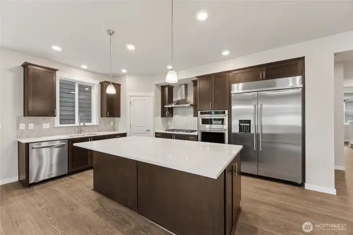 Gourmet kitchen with upgraded appliances including 48" built-in fridge, gas cooktop, standalone vent, wall oven and microwave.  Photos are representational. Actual colors and finishes will vary. See site agent for details.