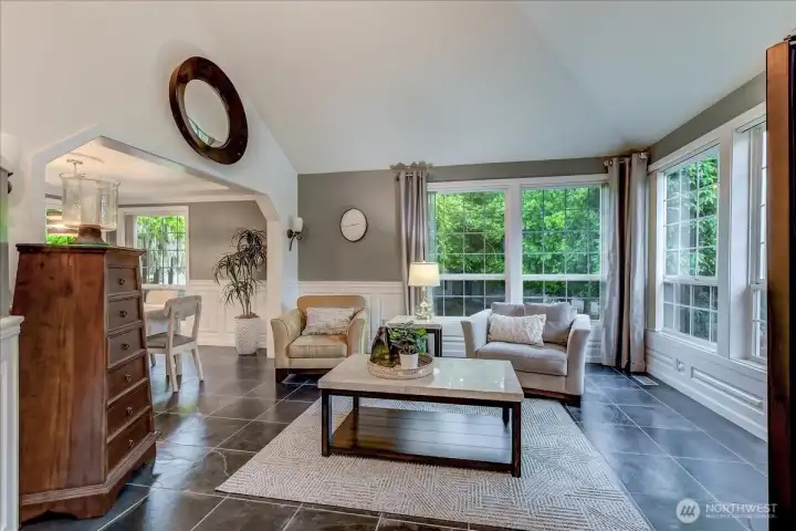 Bright and spacious living room featuring high-end Brazilian slate flooring and large windows that provide abundant natural light.