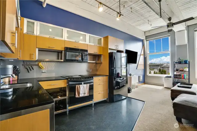 Sleek black and metal detailing, stainless steel, accents with warm wood cabinetry compliment the sleek granite counter tops and easy to clean vinyl flooring. There is plenty of storage in this modern kitchen.