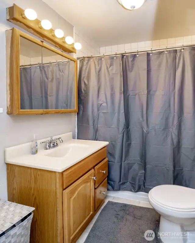 Bright and well-kept, this full bathroom offers everything you need—plus extra storage above the sink to keep your space neat and tidy.