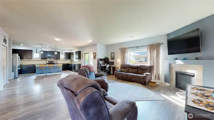 Spacious great room featuring a gas fireplace with tile surround and large windows for natural light