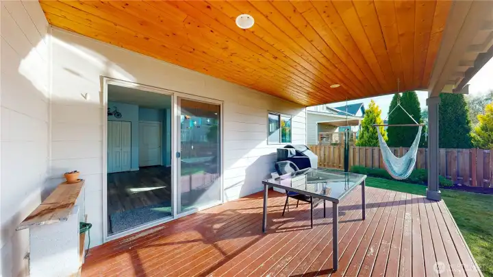 Covered deck with wood-paneled ceiling provides the perfect space for outdoor dining and year-round enjoyment.