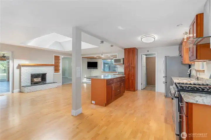 Looking from the dining area towards the kitchen, island and fireplace area. On right side is a family room and on the left side of the fireplace is the very large sunroom.