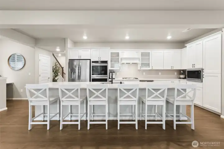 A gourmet kitchen anchors the heart of the home with double ovens and a gas cooktop. An oversized island invites gathering, conversation, and effortless hosting.