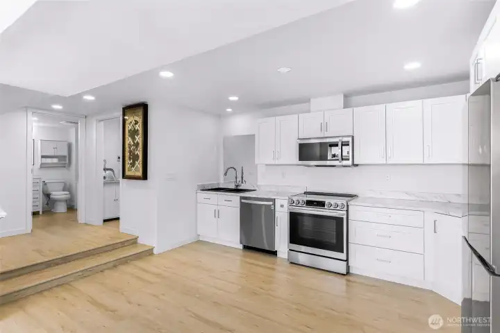 View from living space into kitchen with 3/4 bath directly ahead and full utility room to the right