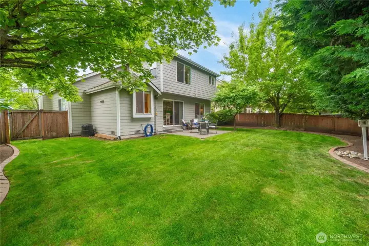 Beautifully landscaped backyard featuring mature trees that provide refreshing shade during the summer months.