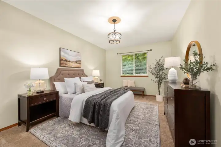 Spacious primary bedroom with new carpet and designer light fixture.