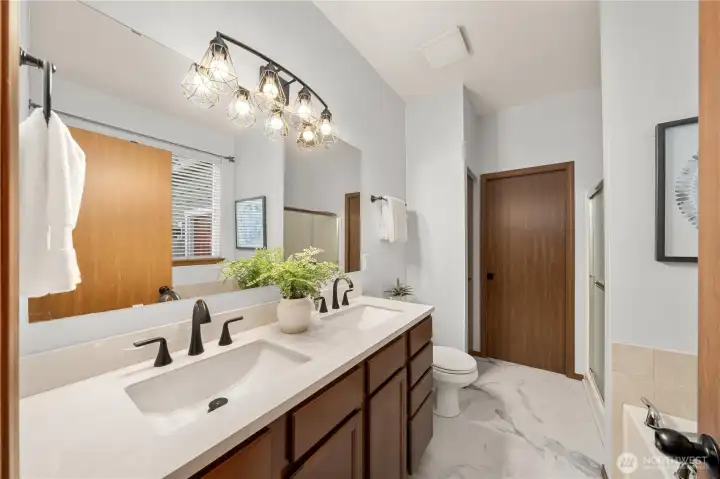 The newly remodeled primary bathroom offers gorgeous, sintered stone countertops, dual sinks, beautiful cabinetry and flooring and designer lighting.