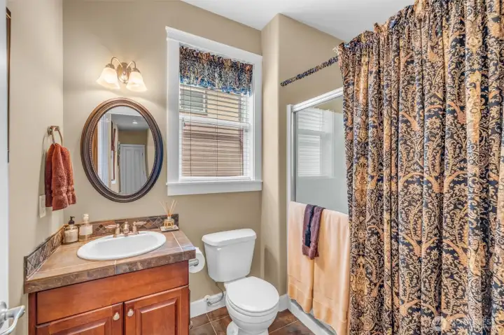 Convenient main-floor 3/4 bath featuring a walk-in shower, tile countertops, and rich wood cabinetry—perfect for guests or multigenerational living. Convenient main-floor 3/4 bath featuring a walk-in shower, tile countertops, and rich wood cabinetry—perfect for guests or multigenerational living.