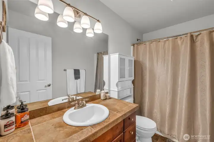 Well-appointed bathroom with tile countertops, generous vanity space, and a full tub/shower combination. Well-appointed bathroom with tile countertops, generous vanity space, and a full tub/shower combination.