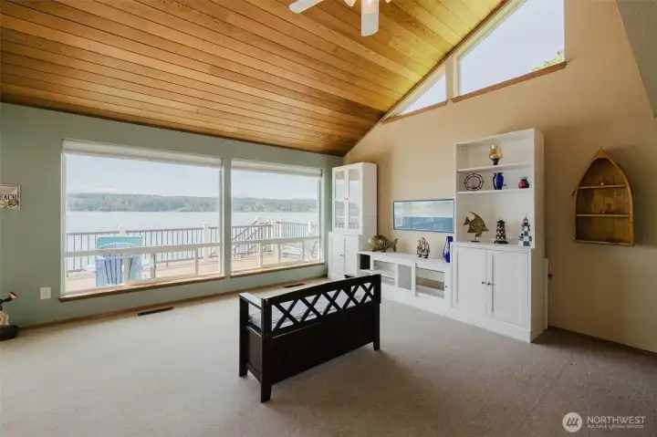 Open, airy, and connected — to the water, to the outdoors, to the kind of easy living you have always hoped for. Clerestory windows tucked high along the roofline pour in additional natural light, keeping the space bright and airy from every angle. Built-in white cabinetry and shelving line one wall — thoughtful storage that keeps the room feeling open and uncluttered while giving you every inch of display space you need for the coastal treasures you'll inevitably collect living here.  The sage green walls echo the water and the tree line just beyond the glass, blurring the line between inside and out in the most effortless way. Spacious, serene, and utterly connected to this one-of-a-kind waterfront setting.