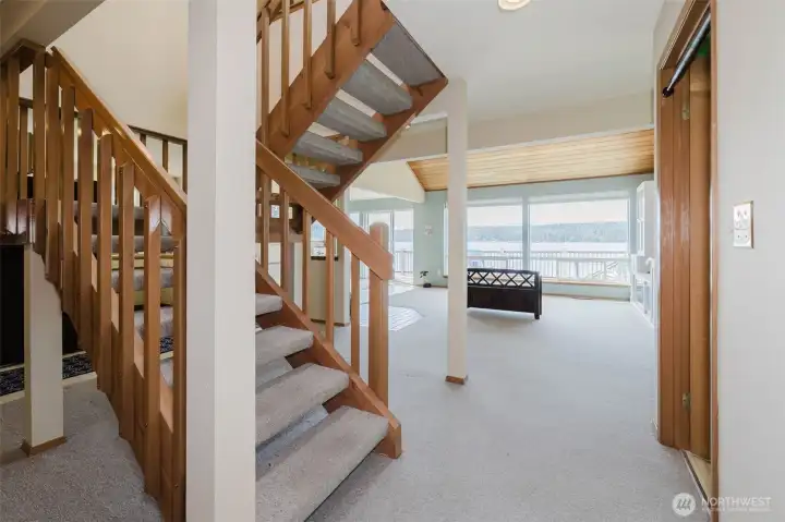 The open staircase in warm natural wood rises boldly to your left — its clean craftsman-style railings and open balusters are a genuine architectural statement, beautiful from every angle and perfectly in keeping with the Pacific Northwest character of this home. It draws the eye up and reminds you there is even more to discover above.  The entry flows immediately and naturally into the generous living space — no awkward foyer, no wasted square footage, just an open, welcoming transition straight into the heart of the home.
