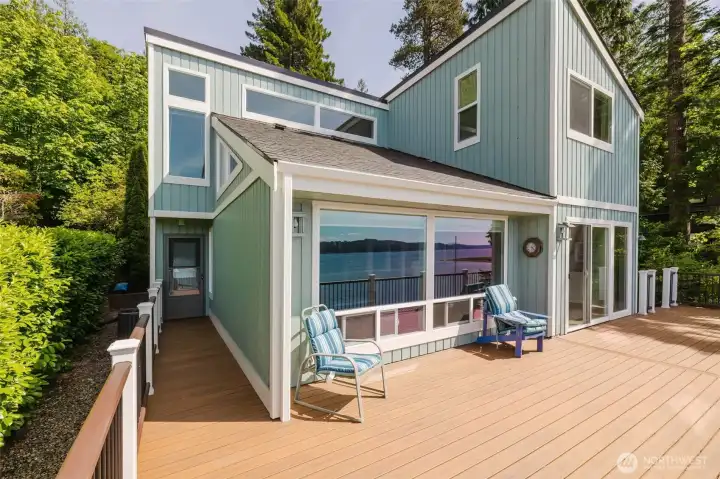 The blue-green siding, the big windows, the deck already dressed for company — it looks like a home that knows exactly what it is. Comfortable. Unpretentious. The kind of place where the door is always open and nobody wants to leave.  From the outside looking in, you can already picture the light pouring through those windows. From the inside looking out, you already know what's waiting. Some homes just feel right before you ever step inside. This is one of them.
