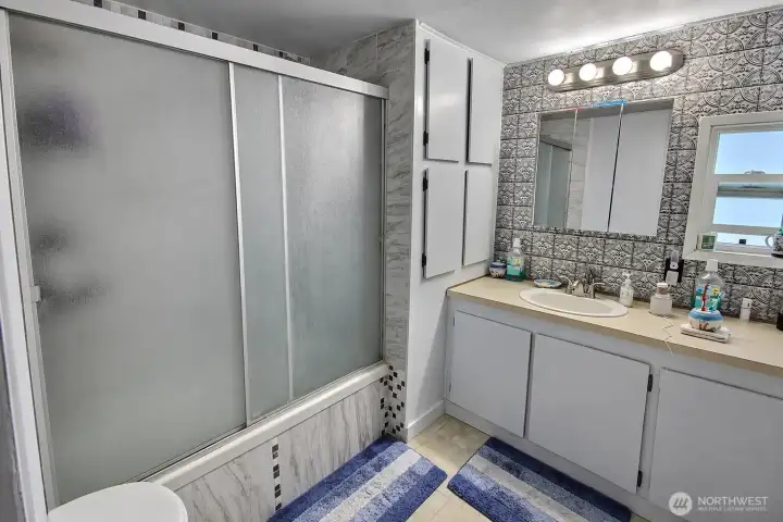 Full bathroom with vanity, mirror lighting, shower enclosure, and storage cabinet. Full bathroom with vanity, mirror lighting, shower enclosure, and storage cabinet.