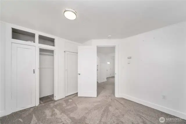 This angle highlights the built-in closet system with overhead storage—perfect for staying organized. The open doorway connects seamlessly to the main living area, giving the room a comfortable and functional layout for everyday living.