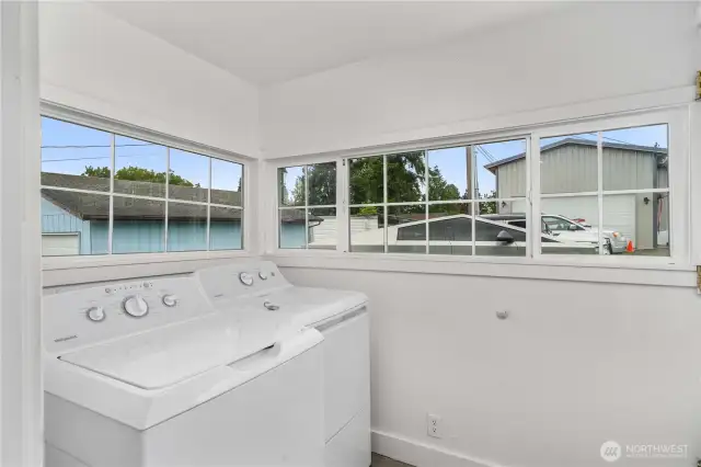 Tucked just off the kitchen, this laundry room is wrapped in windows—filling the space with natural light and making everyday chores feel a little less like work. A practical setup with washer and dryer included, it’s a cheerful and functional bonus to this charming home.