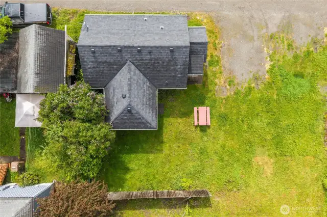 This overhead shot highlights the full layout of the home and yard. Notice the spacious green lawn, alley access, and dedicated area for outdoor seating or entertaining. A great perspective on lot size and layout in relation to neighboring properties.
