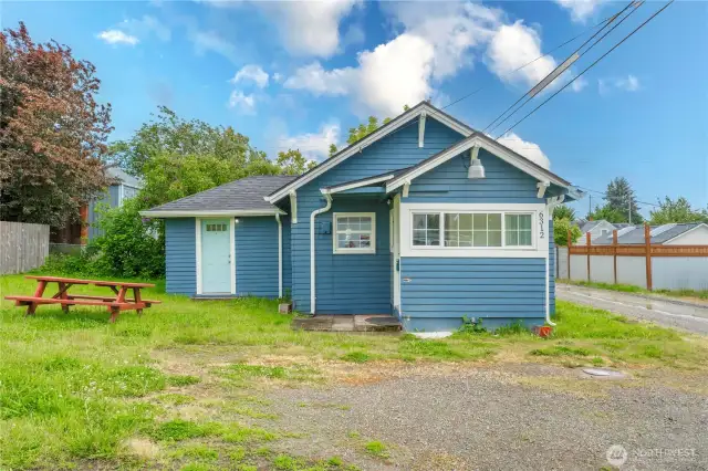 This bright blue exterior invites you in with its crisp white trim and clean lines. The front features dual entry points—one leading through the covered mudroom/laundry area, the other directly into the living room. The open green space and picnic table add a touch of casual charm, perfect for a sunny Tacoma afternoon. A great mix of character and function in a compact footprint!