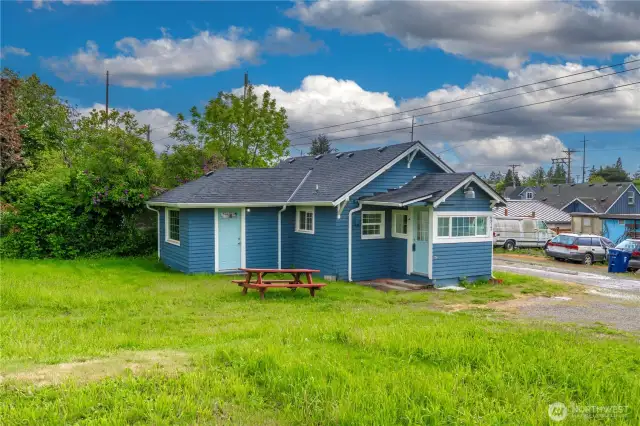 This angle shows both entry points—the covered front entrance into the laundry/mudroom and the second door leading into the living space—plus a roomy yard and alley access, ideal for those seeking a low-maintenance footprint in the city.