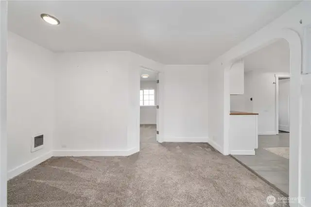 This adaptable living space connects seamlessly to the kitchen and bedroom, offering flexibility for everyday living. The cozy alcove on the left is ideal for a dining table, home office setup, or reading corner—whatever suits your lifestyle. Arched entryways and abundant natural light add charm to this welcoming space.